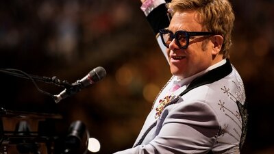 Elton John sitzt während eines Konzerts am Klavier und schaut zum Publikum