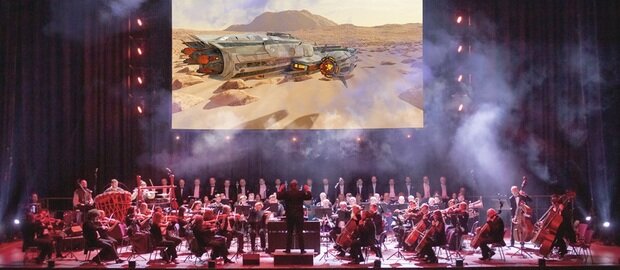 Ein Orchester spielt The Music Of Star Wars, auf der Leinwand wird eine Szene aus dem Film gezeigt