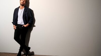 Max Giesinger lehnt sich an weiße Wand.