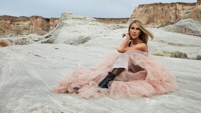 Céline Dion sitzend auf einem Felsen.