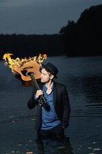 Johannes Oerding mit brennender Gitarre vor der Kulisse eines nöächtlichen Sees