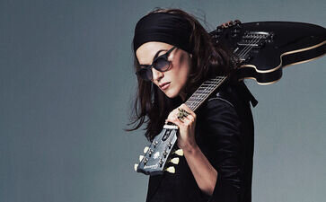 Melody Gardot mit Sonnenbrille und Gitarre lässig über der Schulter