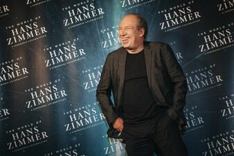 Hans Zimmer steht vor einer Wand mit der Aufschrift "The World of Hans Zimmer"