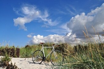 Ein Fahrrad, das vor den Dünen eines Kieler Strandes geparkt worden ist.