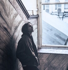 Sänger Lewis Capaldi lehnt an einer Wand und schaut verträumt nach vorn.