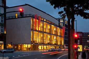 Das Gebäude der Hamburgischen Staatsoper in seitlicher Ansicht und bei nächtlicher Beleuchtung