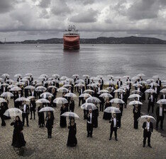 Das Bergen Philharmonic Orchestra posiert mit Regenschirmen im Hafen