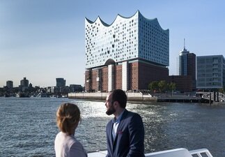 Ein Pärchen sitzt auf der Fähre und blickt auf die Elbphilharmonie. 