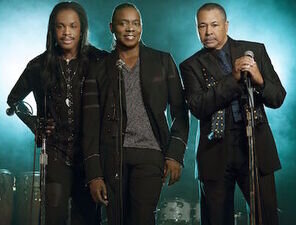 Die Band Earth, Wind and Fire posiert zu dritt in die Kamera.