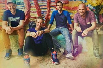 Die Vier der Band Coldplay sitzen lachend beieinander.