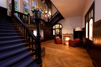 Villla Papendorf Innenraum mit Treppe, Sessel und Kamin