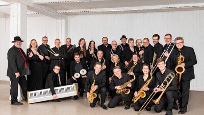 Die SBR Bigband in einem Foyer mit Instrumenten in der Hand